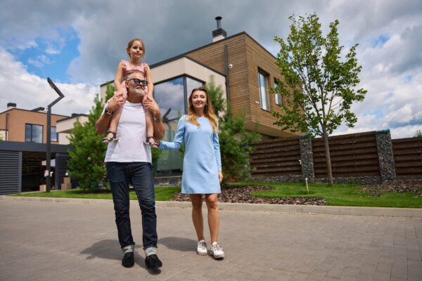 Photo of happy family on background of cottage and pines. Moving to new home